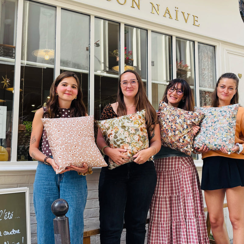 Participantes à un atelier couture devant la boutique La Maison Naïve à Paris 10 tenant leurs coussins cousus main